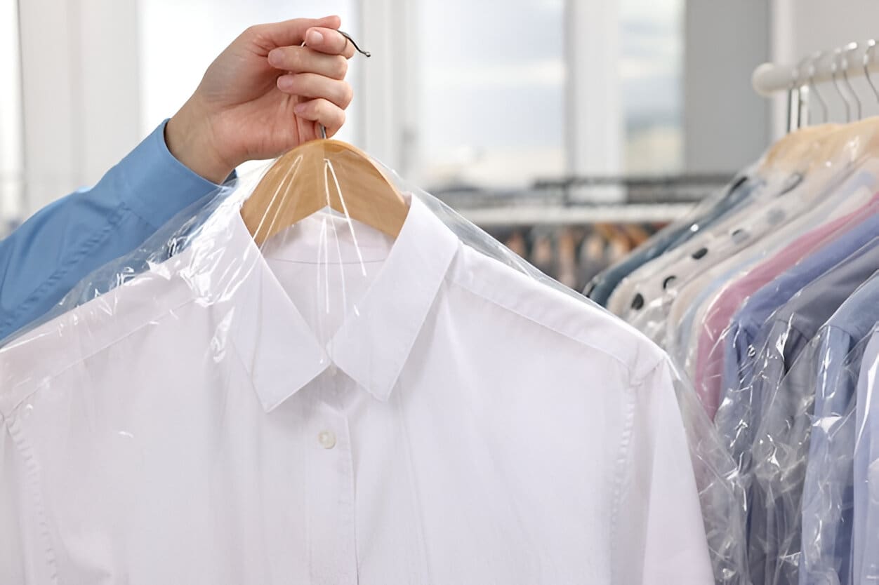 Person holding freshly cleaned white dress shirt in plastic garment bag, showcasing laundry and dry cleaning services by My Best Cleaners in Clinton, Maryland.