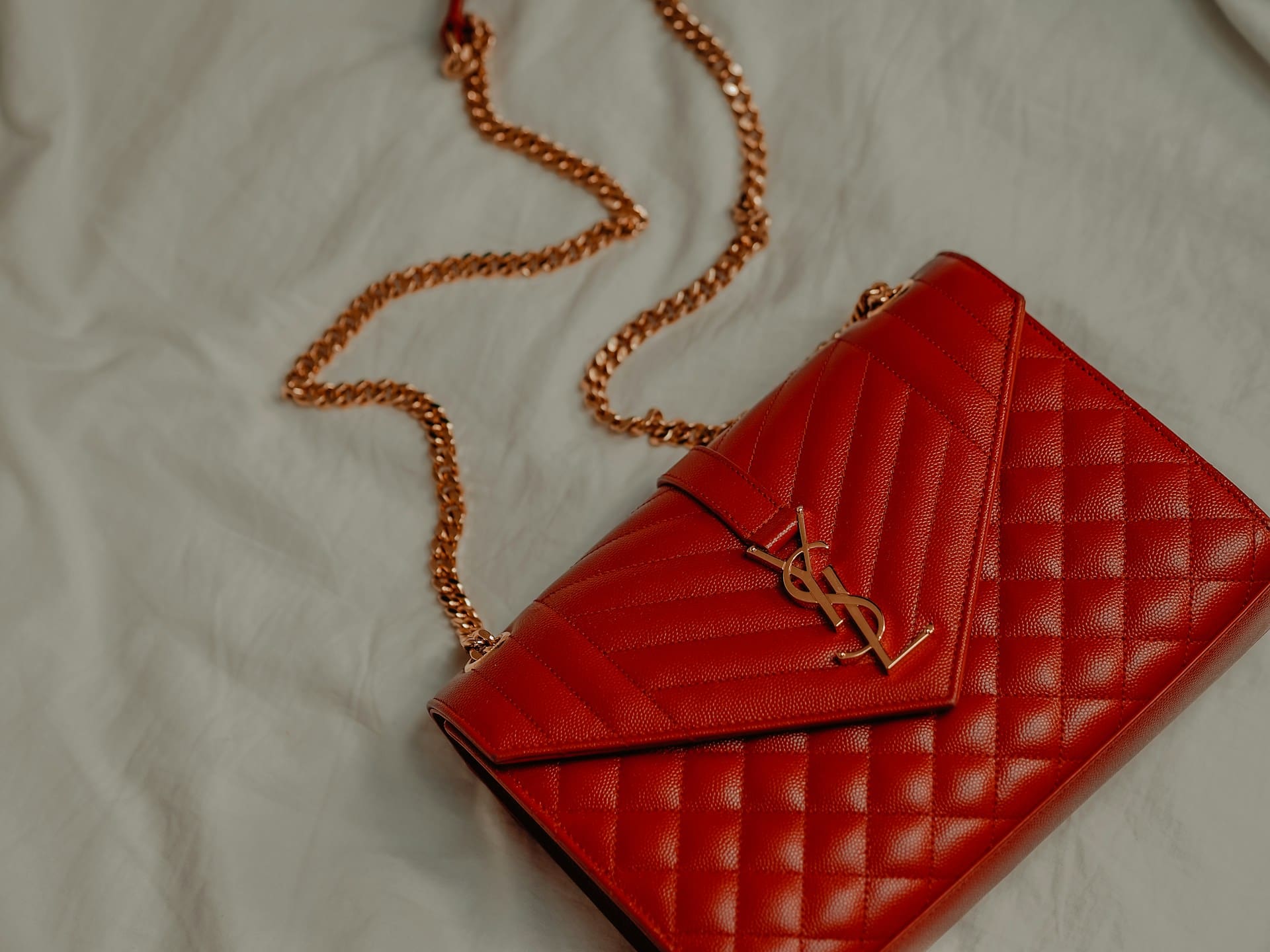 Red leather handbag with gold chain strap and YSL logo, emphasizing luxury and quality care for leather and suede items at My Best Cleaners.
