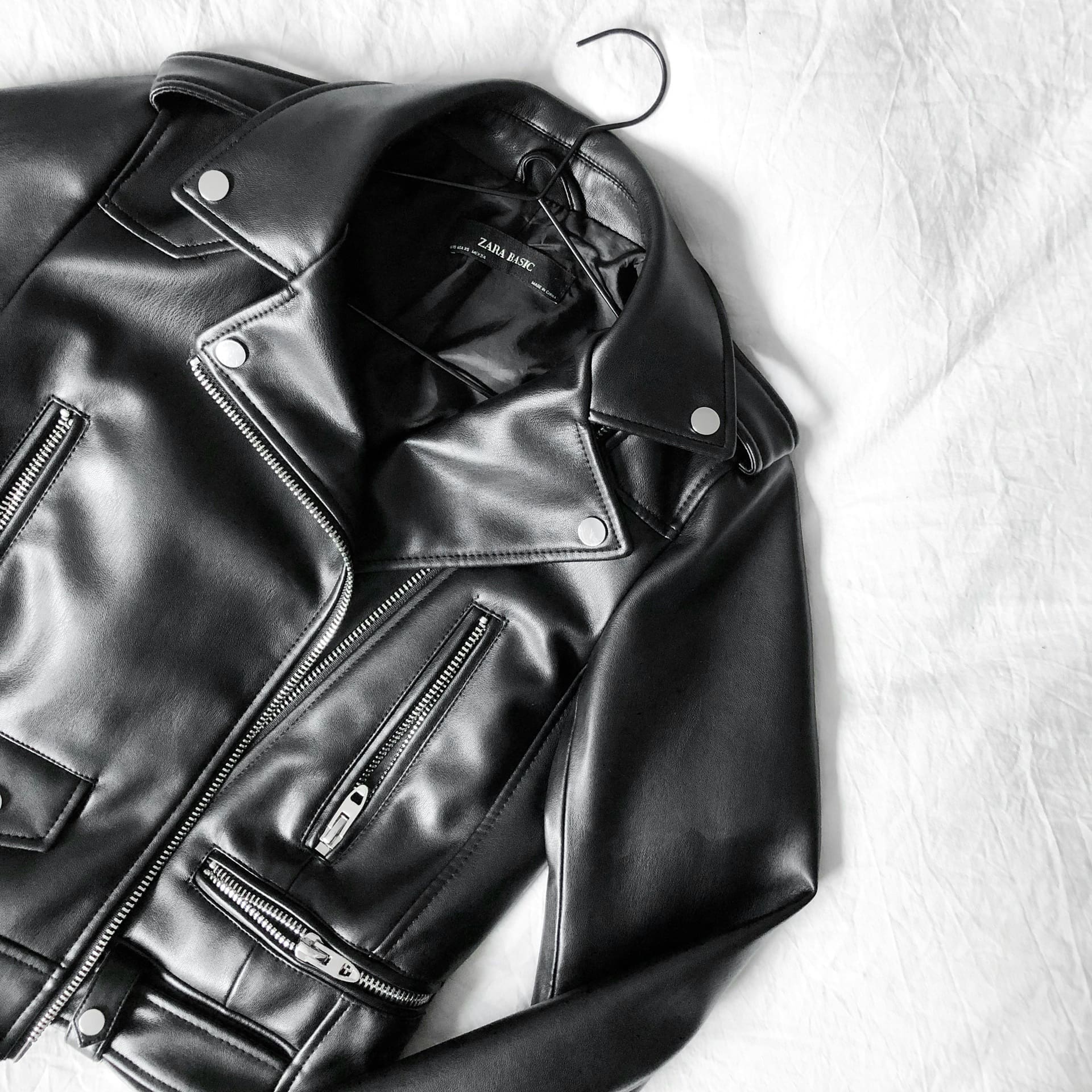 Black leather motorcycle jacket on a hanger, showcasing zippers and sleek design, relevant to My Best Cleaners' leather and suede cleaning services.